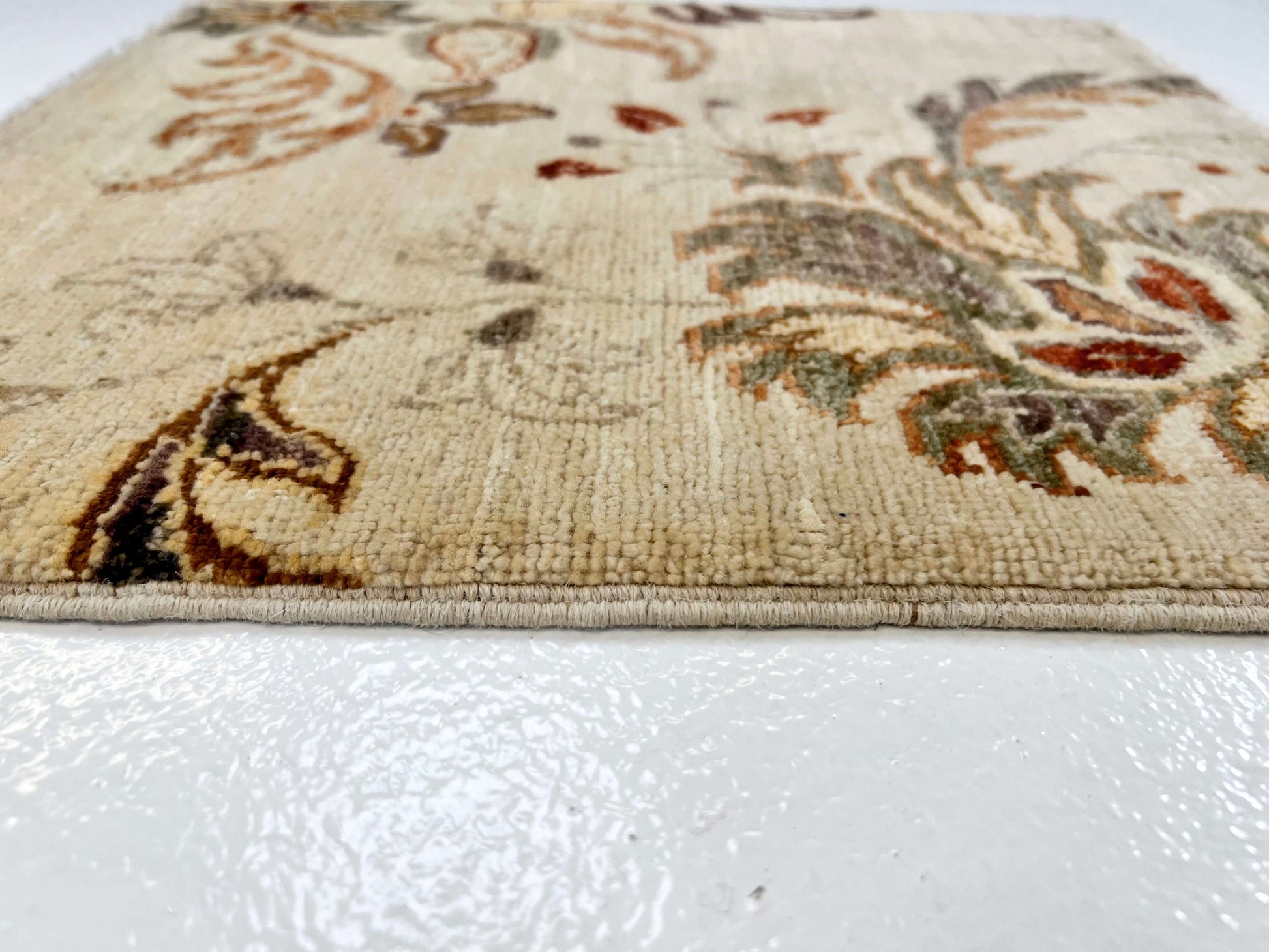 Edge details of 18" square ivory rug features vegetable-dyed wool with luxurious silk accents